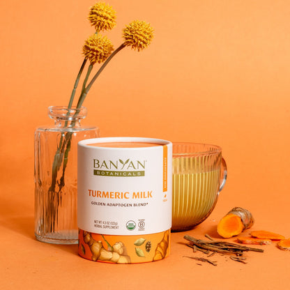 Mug of turmeric milk next to product packaging on orange background